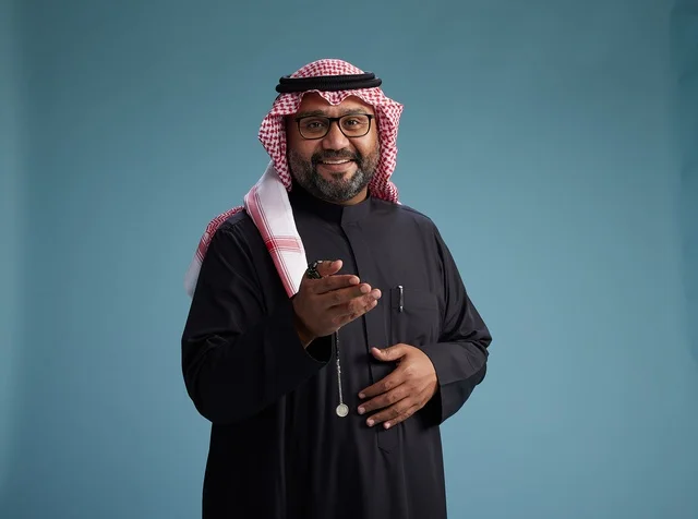 A smiling Saudi man wearing a black thobe with a shemagh and agal, with various hand gestures and movements, against a blue background.