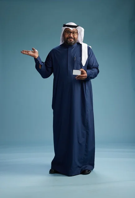 A portrait of a Saudi man wearing a navy thobe and a white ghutrah, holding a credit card and standing, full body, with a blank white card, against a blue background.
