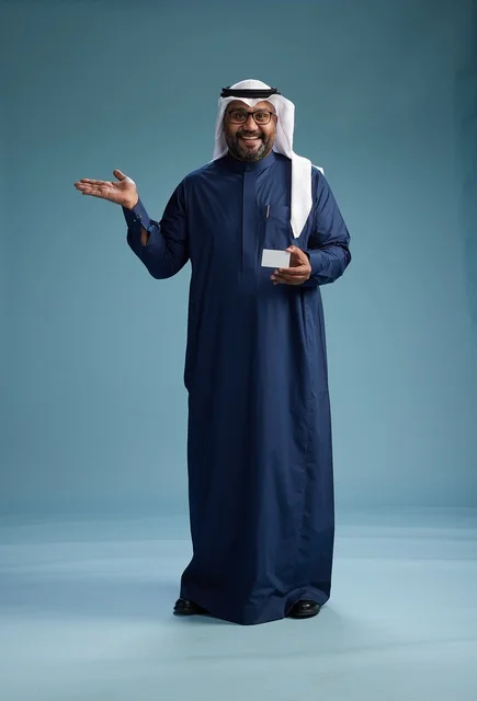 A portrait of a Saudi man wearing a navy thobe and a white ghutrah, holding a credit card and standing, full body, with a blank white card, against a blue background.