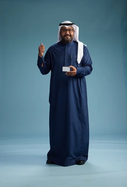 A portrait of a Saudi man wearing a navy thobe and a white ghutrah, holding a credit card and standing, full body, with a blank white card, against a blue background.