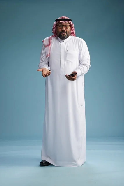 بورتريه لرجل  عربي سعودي  خليجي يرتدي الثوب الابيض والشماغ يستخدم الهاتف الذكي, ايماءات وحركات متنوعه , الجسم بالطول الكامل, خلفيه زرقاء