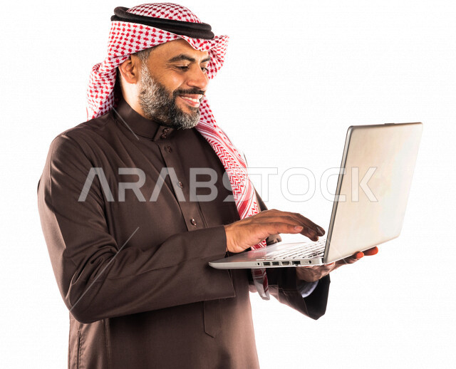 Portrait of a Saudi Arabian Gulf man holding a laptop computer, accomplishing tasks through the laptop, working remotely, modern technical devices, using modern technologies, white background