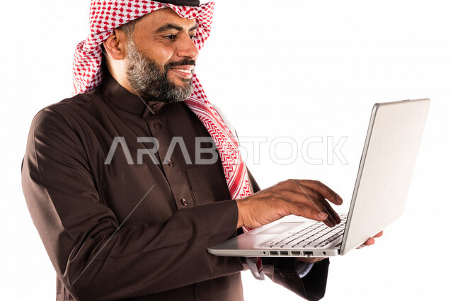 بورتريه لرجل عربي خليجي سعودي يحمل بيده جهاز حاسوب محمول، انجاز المهام من خلال الحاسوب المحمول، العمل عن بعد، أجهزة تقنية حديثة، استخدام تقنيات حديثة، خلفية بيضاء