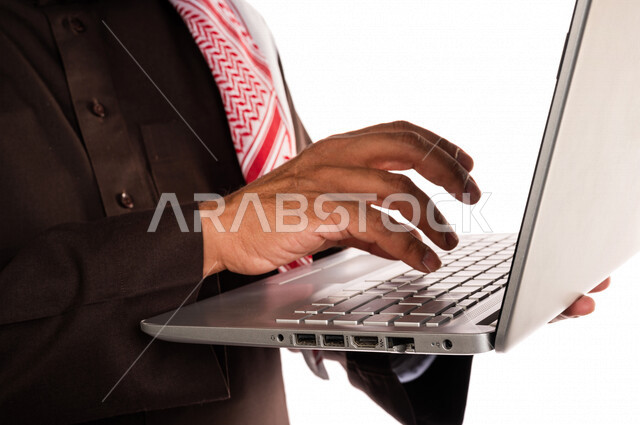 بورتريه لرجل عربي خليجي سعودي يحمل بيده جهاز حاسوب محمول، انجاز المهام من خلال الحاسوب المحمول، العمل عن بعد، أجهزة تقنية حديثة، استخدام تقنيات حديثة، خلفية بيضاء