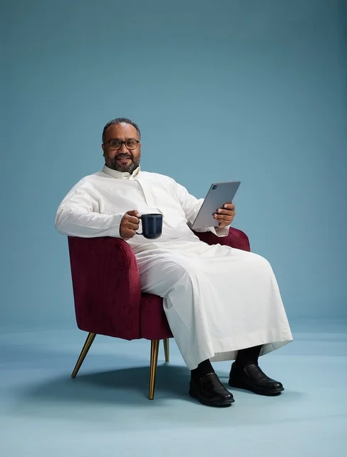 A Saudi man in traditional attire holding a tablet, using the mobile tablet, various gestures and movements, blue background.