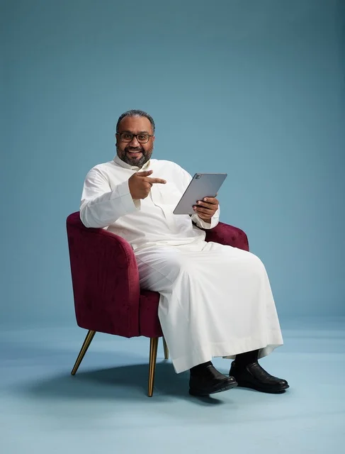 A Saudi man in traditional attire holding a tablet, using the mobile tablet, various gestures and movements, blue background.