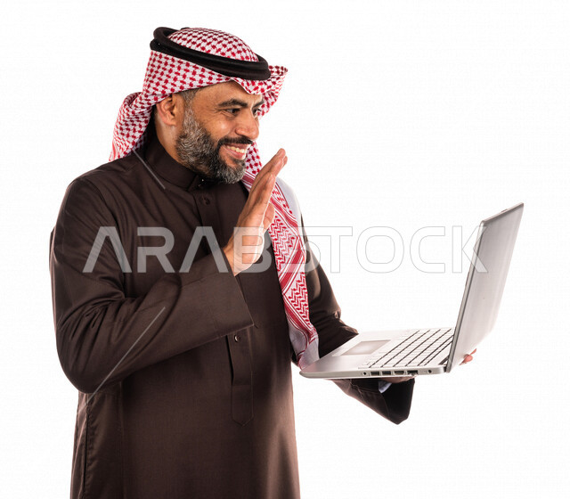بورتريه لرجل عربي خليجي سعودي يحمل بيده جهاز حاسوب محمول، اجراء مكالمات فيديو اونلاين، تواصل اجتماعي، محادثات ودردشة، التواصل مع الأصدقاء، اجتماع عمل عن بعد، بث فيديو مباشر، خلفية بيضاء