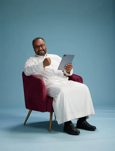 رجل سعودي بالزي التقليدي يحمل جهاز لوحي, استخدام التابليت المحمول, ايماءات وحركات متنوعه, خلفيه زرقاء