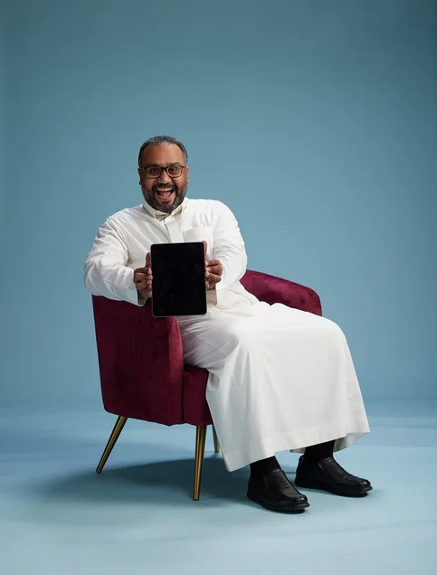 A Saudi man in traditional attire holding a tablet, using the mobile tablet, various gestures and movements, blue background.