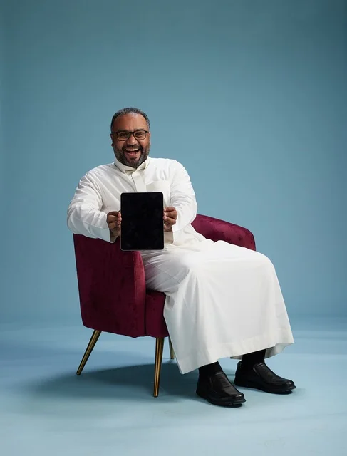 A Saudi man in traditional attire holding a tablet, using the mobile tablet, various gestures and movements, blue background.