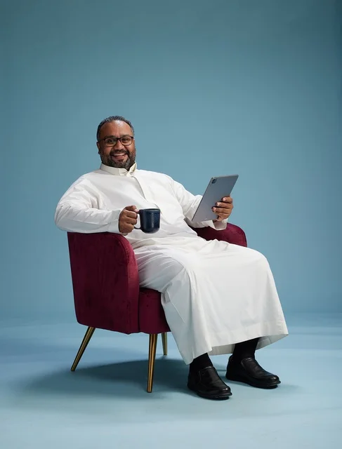 A Saudi man in traditional attire holding a tablet, using the mobile tablet, various gestures and movements, blue background.