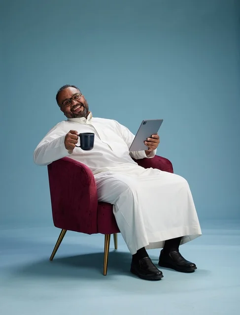 A Saudi man in traditional attire holding a tablet, using the mobile tablet, various gestures and movements, blue background.