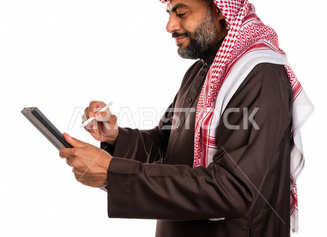 بورتريه لرجل عربي خليجي سعودي يستخدم التابليت المحمول، التسويق الإلكتروني، العمل عن بعد، استخدام قلم التابليت لتدوين الملاحظات، استخدام تقنيات حديثة، خلفية بيضاء