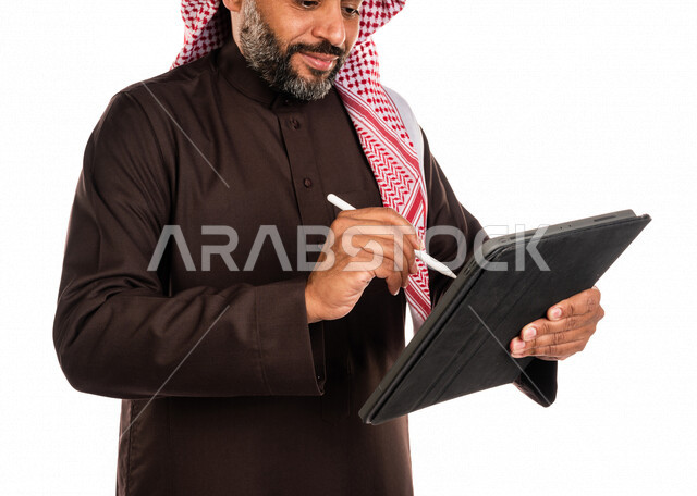 بورتريه لرجل عربي خليجي سعودي يستخدم التابليت المحمول، التسويق الإلكتروني، العمل عن بعد، استخدام قلم التابليت لتدوين الملاحظات، استخدام تقنيات حديثة، خلفية بيضاء