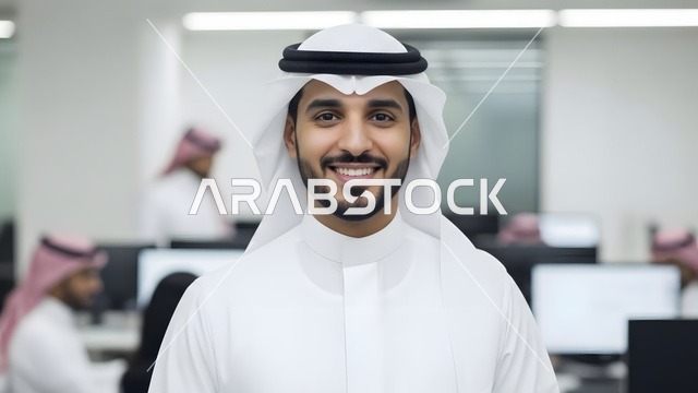النظر الى الكاميرا بتعابير السرور ، تكنولوجيا الأعمال في الامارات العربيه المتحده، تصوير مقرب لموظف امارتي مبتسم يرتدي الكندورة والغترة البيضاء في مكتب عصري، بيئة عمل احترافية، مفهوم الإتقان والتركيز