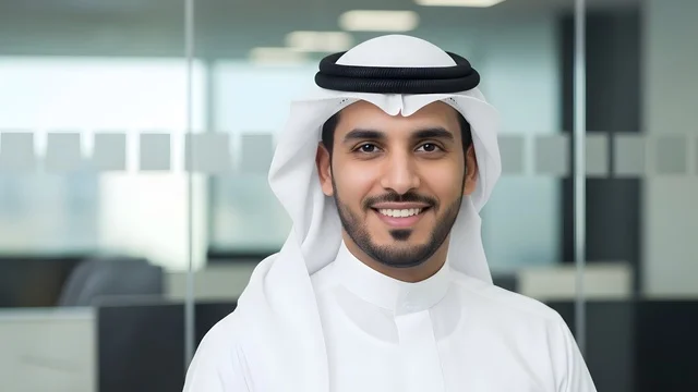 Looking at the camera with expressions of joy, business technology in the United Arab Emirates, a close-up shot of a smiling Emirati employee wearing the kandura and white ghutrah in a modern office, a professional work environment, the concept of perfection and focus.