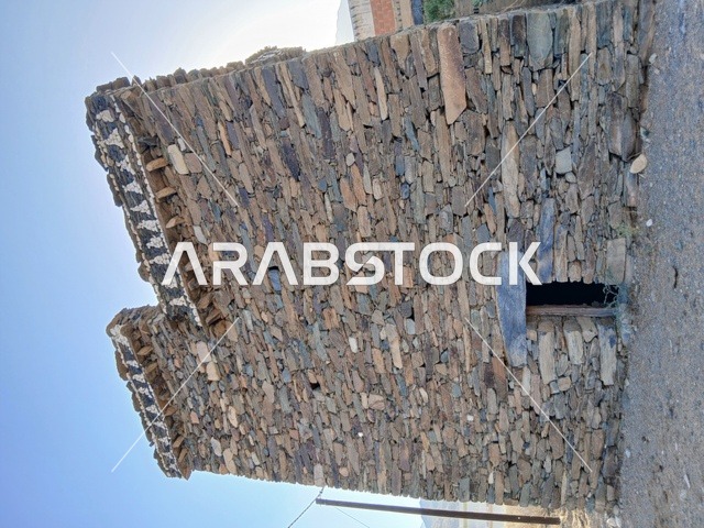 البيوت الحجرية القديمة على الجبال في منطقة الباحة في قرية ذي العين الأثرية جنوب المملكة العربية السعودية، المعالم السياحية التاريخية المشهورة، الأشجار والنباتات الخضراء المحيطة بالقرية على المرتفعات والقمم الجبلية