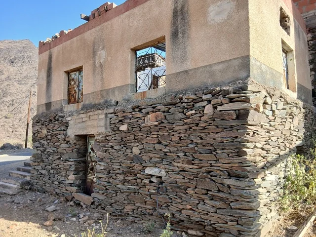 البيوت الحجرية القديمة على الجبال في منطقة الباحة في قرية ذي العين الأثرية جنوب المملكة العربية السعودية، المعالم السياحية التاريخية المشهورة، الأشجار والنباتات الخضراء المحيطة بالقرية على المرتفعات والقمم الجبلية