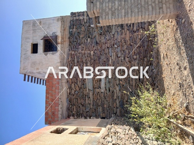 البيوت الحجرية القديمة على الجبال في منطقة الباحة في قرية ذي العين الأثرية جنوب المملكة العربية السعودية، المعالم السياحية التاريخية المشهورة، الأشجار والنباتات الخضراء المحيطة بالقرية على المرتفعات والقمم الجبلية