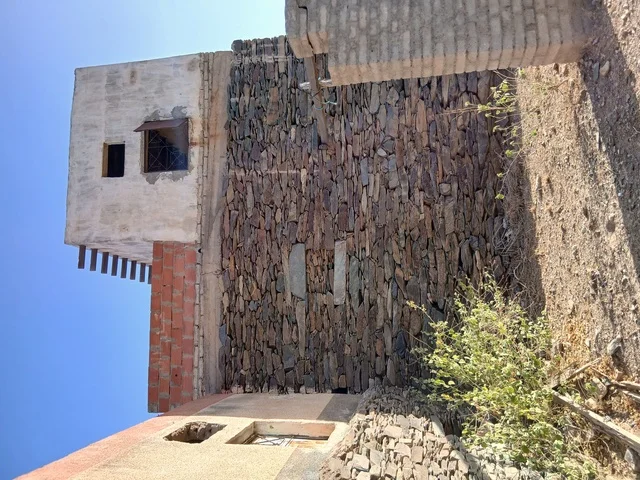 The old stone houses on the mountains in the Al-Baha region in the archaeological village of Dhai Ain, south of the Kingdom of Saudi Arabia, are famous historical tourist landmarks, surrounded by green trees and plants on the highlands and mountain peaks.