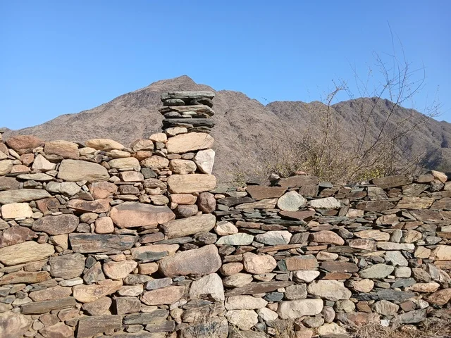 البيوت الحجرية القديمة على الجبال في منطقة الباحة في قرية ذي العين الأثرية جنوب المملكة العربية السعودية، المعالم السياحية التاريخية المشهورة، الأشجار والنباتات الخضراء المحيطة بالقرية على المرتفعات والقمم الجبلية