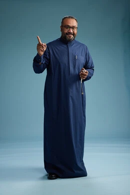 A portrait of a Saudi man standing wearing a navy blue thobe, making various gestures and movements, standing full body, with a blue background.