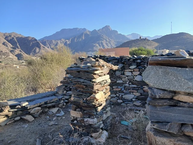 المعالم السياحية التاريخية المشهورة،  البيوت الحجرية القديمة على الجبال في منطقة الباحة في قرية ذي العين الأثرية جنوب المملكة العربية السعودية، الأشجار والنباتات الخضراء المحيطة بالقرية على المرتفعات والقمم الجبلية