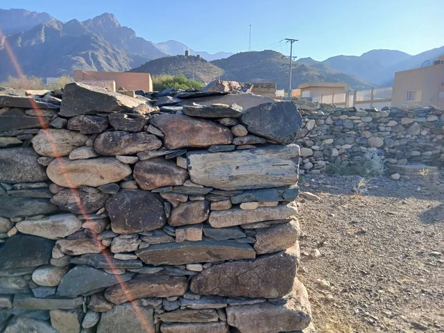 المعالم السياحية التاريخية المشهورة،  البيوت الحجرية القديمة على الجبال في منطقة الباحة في قرية ذي العين الأثرية جنوب المملكة العربية السعودية، الأشجار والنباتات الخضراء المحيطة بالقرية على المرتفعات والقمم الجبلية