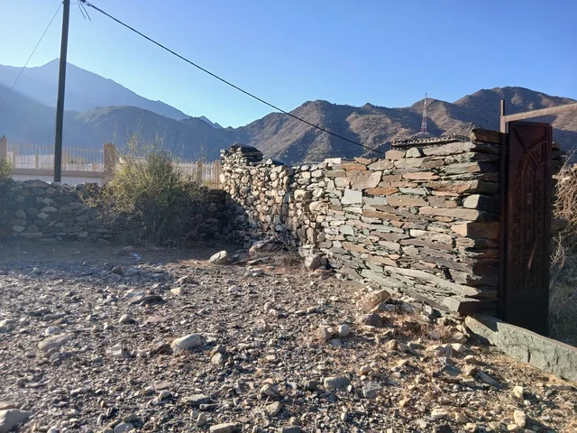 المعالم السياحية التاريخية المشهورة،  البيوت الحجرية القديمة على الجبال في منطقة الباحة في قرية ذي العين الأثرية جنوب المملكة العربية السعودية، الأشجار والنباتات الخضراء المحيطة بالقرية على المرتفعات والقمم الجبلية