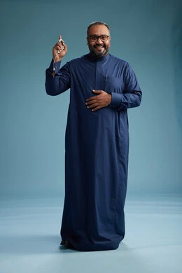 A portrait of a Saudi man standing wearing a navy blue thobe, making various gestures and movements, standing full body, with a blue background.