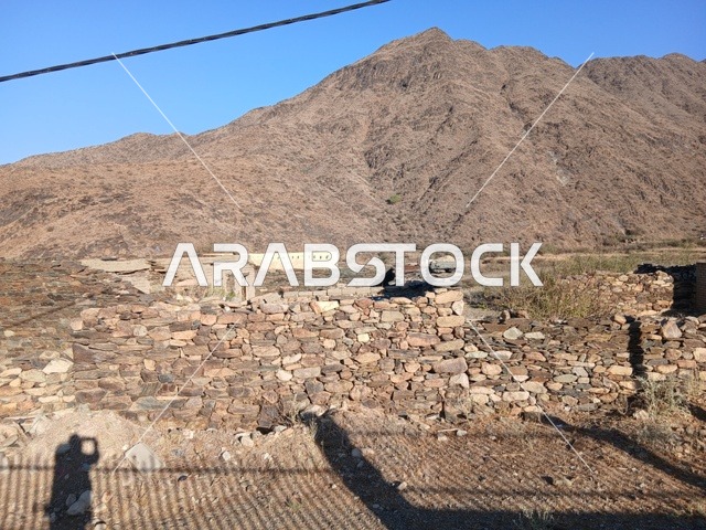 المعالم السياحية التاريخية المشهورة،  البيوت الحجرية القديمة على الجبال في منطقة الباحة في قرية ذي العين الأثرية جنوب المملكة العربية السعودية، الأشجار والنباتات الخضراء المحيطة بالقرية على المرتفعات والقمم الجبلية