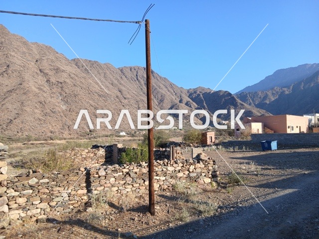 المعالم السياحية التاريخية المشهورة،  البيوت الحجرية القديمة على الجبال في منطقة الباحة في قرية ذي العين الأثرية جنوب المملكة العربية السعودية، الأشجار والنباتات الخضراء المحيطة بالقرية على المرتفعات والقمم الجبلية