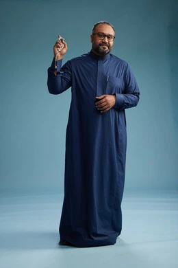 بورتريه لرجل سعودي يقف مرتدياً ثوب كحلي يقوم بايماءات وحركات متنوعه, الوقوف بكامل الجسم, خلفيه زرقاء