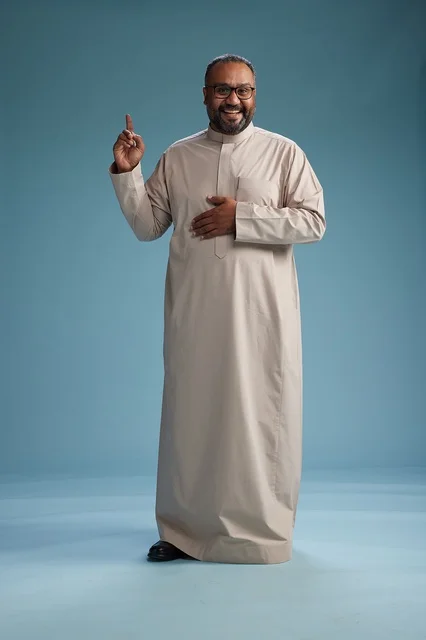 A smiling Saudi man wearing a beige thobe with various hand gestures and movements, full body, blue background.