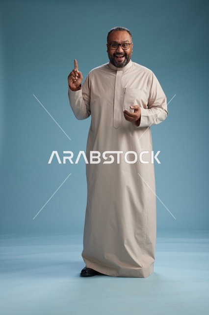 رجل سعودي مبتسم يرتدي ثوب بيج بايماءات وحركات يد متنوعه, كامل الجسم, خلفيه زرقاء