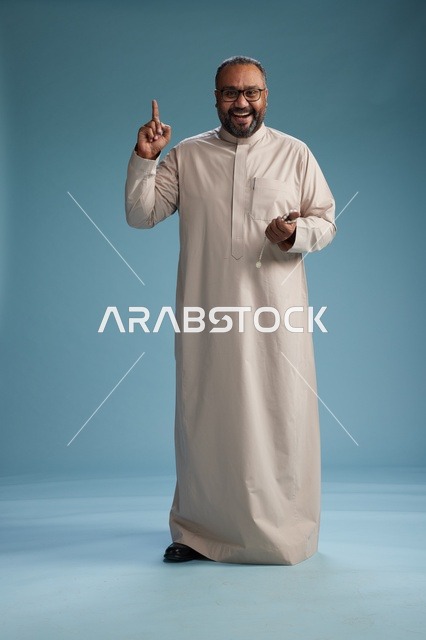 A smiling Saudi man wearing a beige thobe with various hand gestures and movements, full body, blue background.