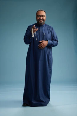 بورتريه لرجل سعودي يقف مرتدياً ثوب كحلي يقوم بايماءات وحركات متنوعه, الوقوف بكامل الجسم, خلفيه زرقاء