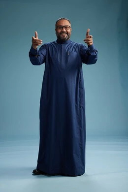 بورتريه لرجل سعودي يقف مرتدياً ثوب كحلي يقوم بايماءات وحركات متنوعه, الوقوف بكامل الجسم, خلفيه زرقاء