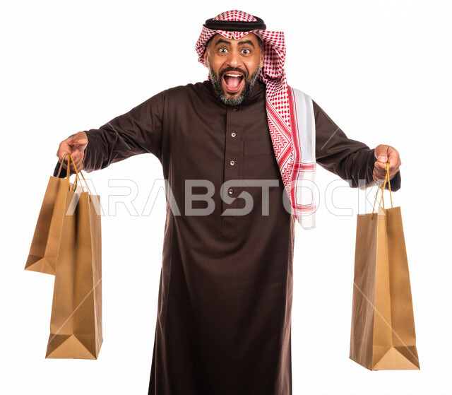 Portrait of a Saudi Arabian Gulf man carrying his purchases, returning from the market, the pleasure of shopping, buying necessary items, clearances and discounts, Black Friday, White Friday, discounts and sales, a Saudi man carrying shopping bags, white
