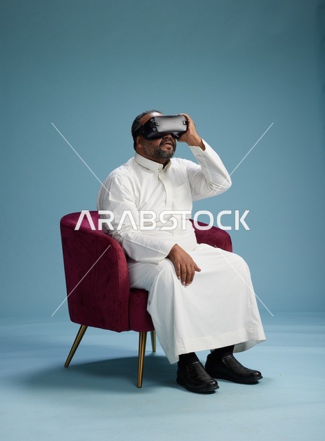 رجل سعودي بالزي التقليدي يخوض تجربة واقع افتراضي, مشاهدة افلام الفي ار, خلفيه زرقاء