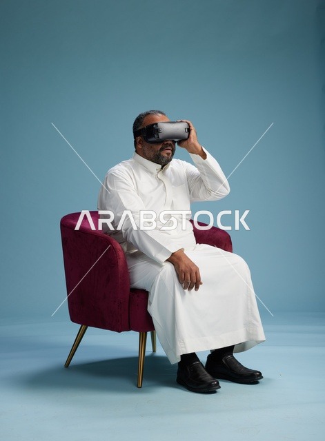 رجل سعودي بالزي التقليدي يخوض تجربة واقع افتراضي, مشاهدة افلام الفي ار, خلفيه زرقاء