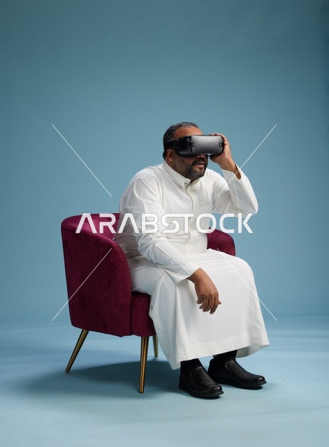 رجل سعودي بالزي التقليدي يخوض تجربة واقع افتراضي, مشاهدة افلام الفي ار, خلفيه زرقاء