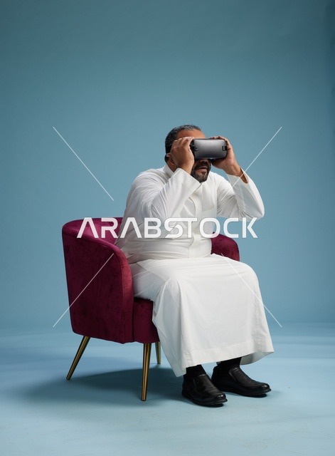 رجل سعودي بالزي التقليدي يخوض تجربة واقع افتراضي, مشاهدة افلام الفي ار, خلفيه زرقاء
