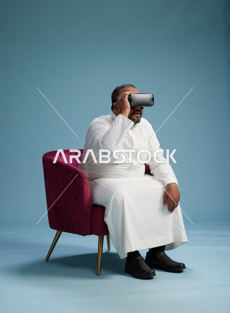 رجل سعودي بالزي التقليدي يخوض تجربة واقع افتراضي, مشاهدة افلام الفي ار, خلفيه زرقاء