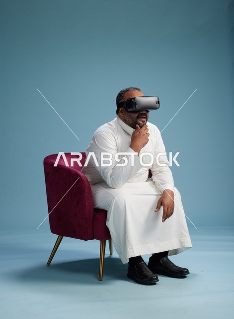 رجل سعودي بالزي التقليدي يخوض تجربة واقع افتراضي, مشاهدة افلام الفي ار, خلفيه زرقاء