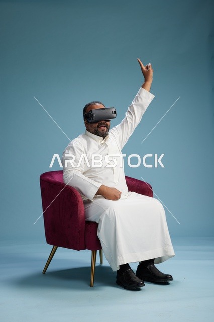 رجل سعودي بالزي التقليدي يخوض تجربة واقع افتراضي, مشاهدة افلام الفي ار, خلفيه زرقاء