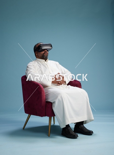 رجل سعودي بالزي التقليدي يخوض تجربة واقع افتراضي, مشاهدة افلام الفي ار, خلفيه زرقاء