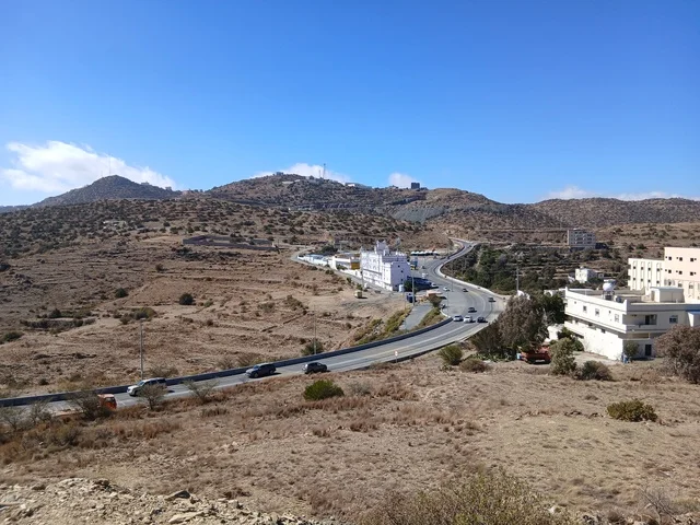 البيوت السكنية والطرقات المهيئة في المدينة، المعالم السياحية التاريخية المشهورة، منطقة الباحة في قرية ذي العين الأثرية جنوب المملكة العربية السعودية، الأشجار والنباتات الخضراء المحيطة بالقرية على المرتفعات والقمم الجبلية