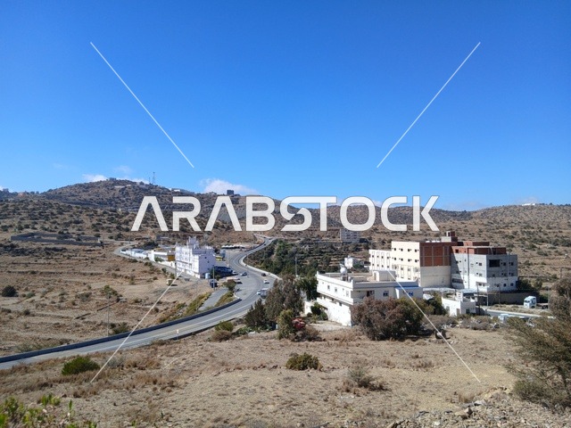 البيوت السكنية والطرقات المهيئة في المدينة، المعالم السياحية التاريخية المشهورة، منطقة الباحة في قرية ذي العين الأثرية جنوب المملكة العربية السعودية، الأشجار والنباتات الخضراء المحيطة بالقرية على المرتفعات والقمم الجبلية