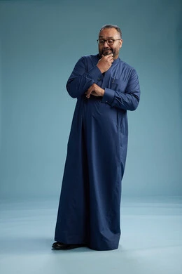 A portrait of a Saudi man standing wearing a navy blue thobe, making various gestures and movements, standing full body, with a blue background.